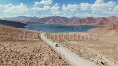 在4x4路的高空，汽车沿着砾石小径驶向干旱山区的湖泊。 帕米尔公路丝绸之路